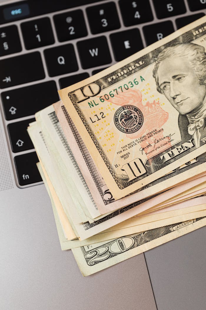 Close-up of US dollar bills stacked on a laptop keyboard, representing online finance.